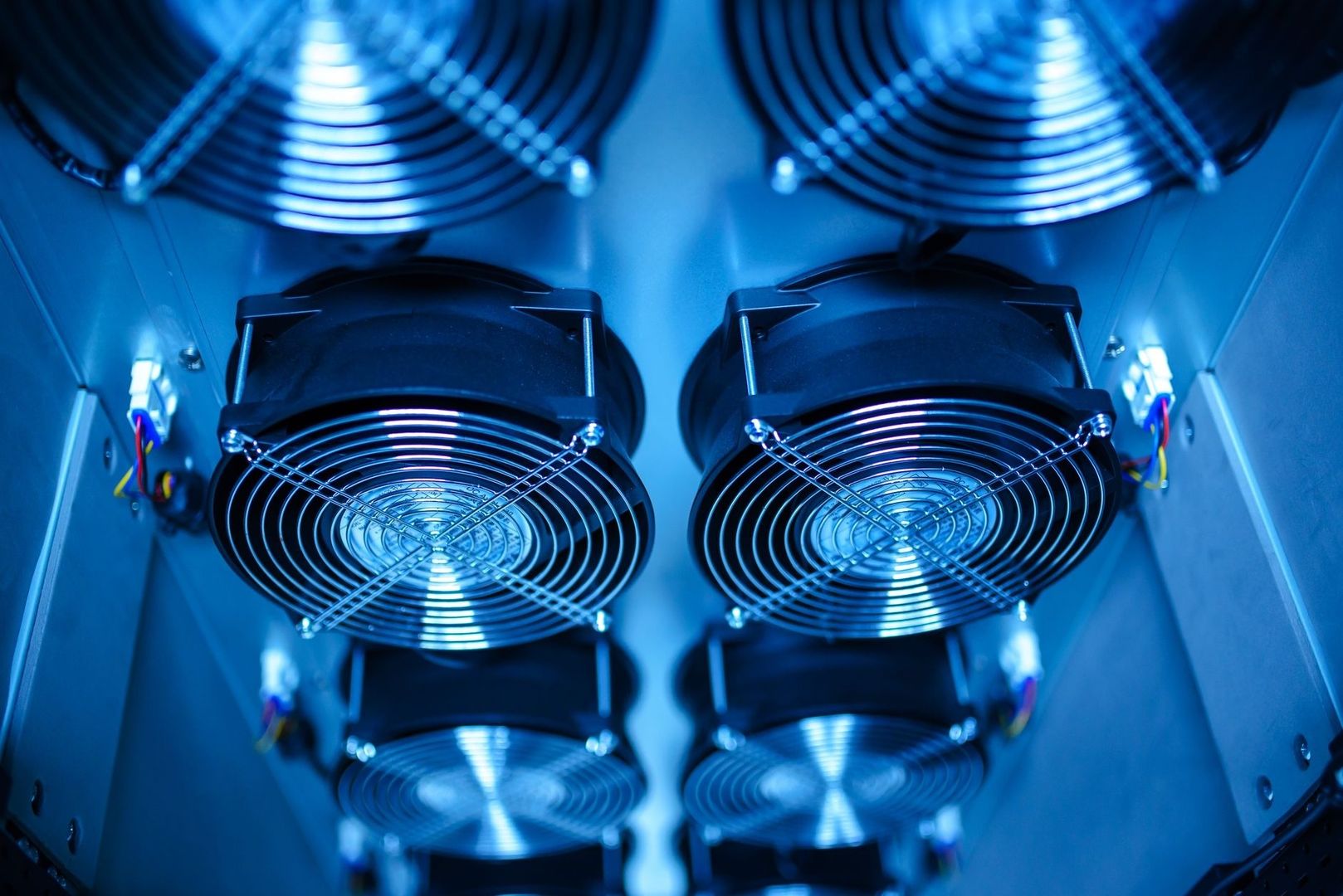 Mehrere große Lüfter mit Schutzgittern in einem blau beleuchteten Technikgehäuse